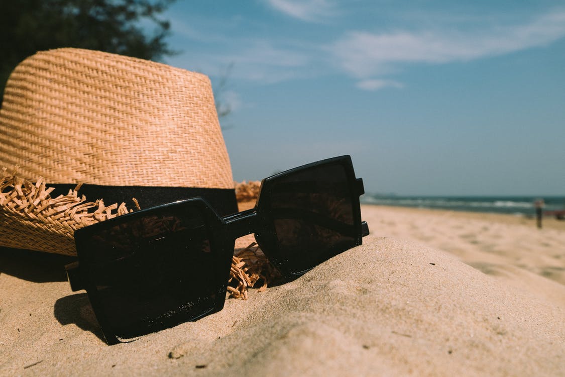 Straw hat and sunglasses on the sand