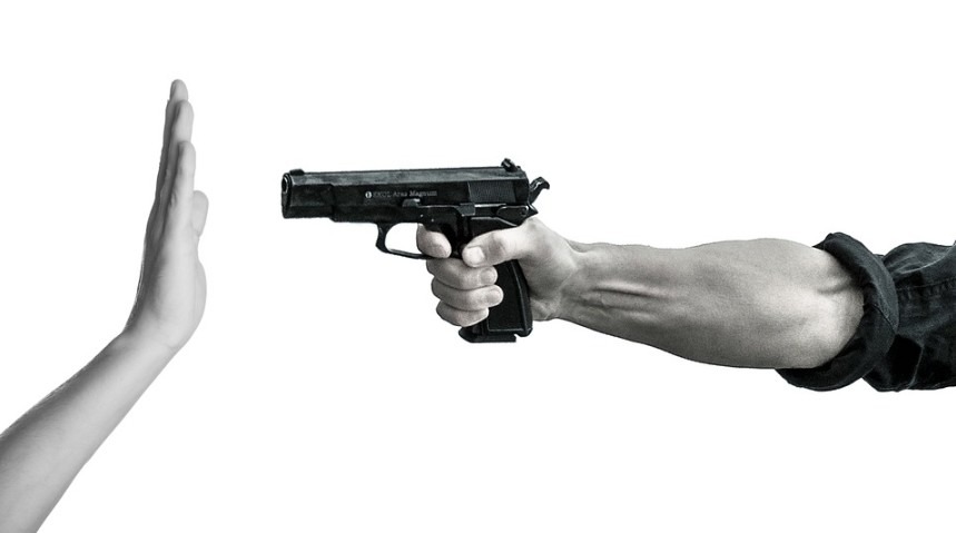 Hand signaling stop to a handgun pointed to it